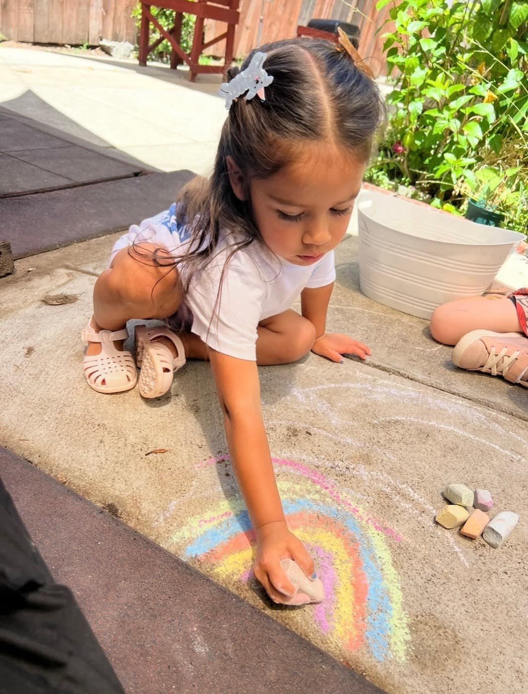 Drawing a chalk rainbow on the sidewalk