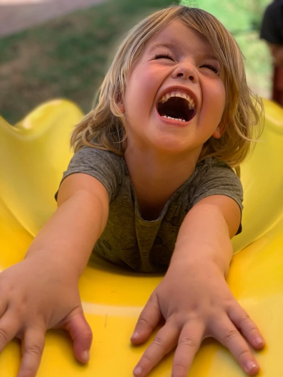 A child laughing with pure joy on the slide